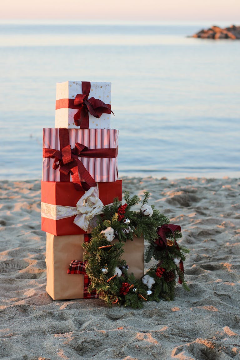 Festive holiday gifts and wreath on a serene beach for a unique Christmas theme.