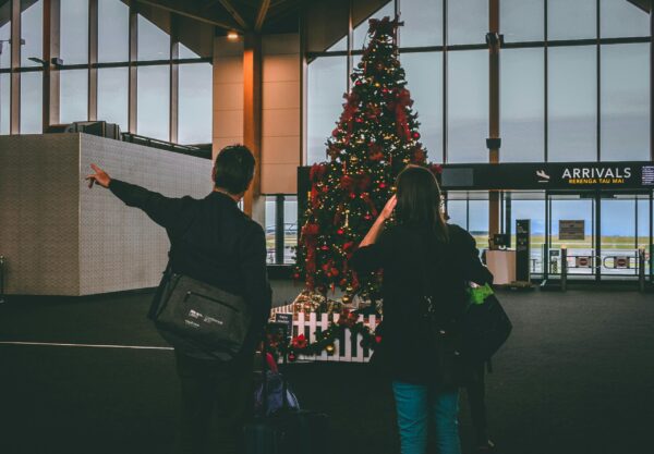 Young couple observes Christmas tree inside airport terminal.