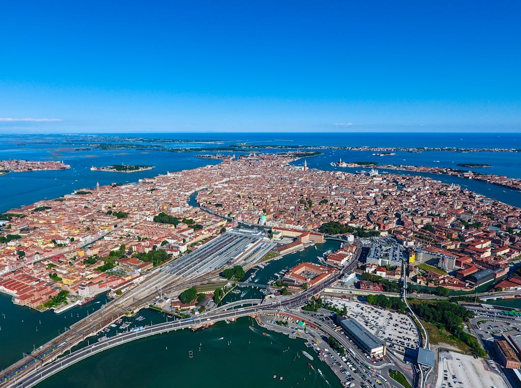 Stunning aerial photograph capturing the iconic cityscape of Venice surrounded by blue waters on a sunny day.